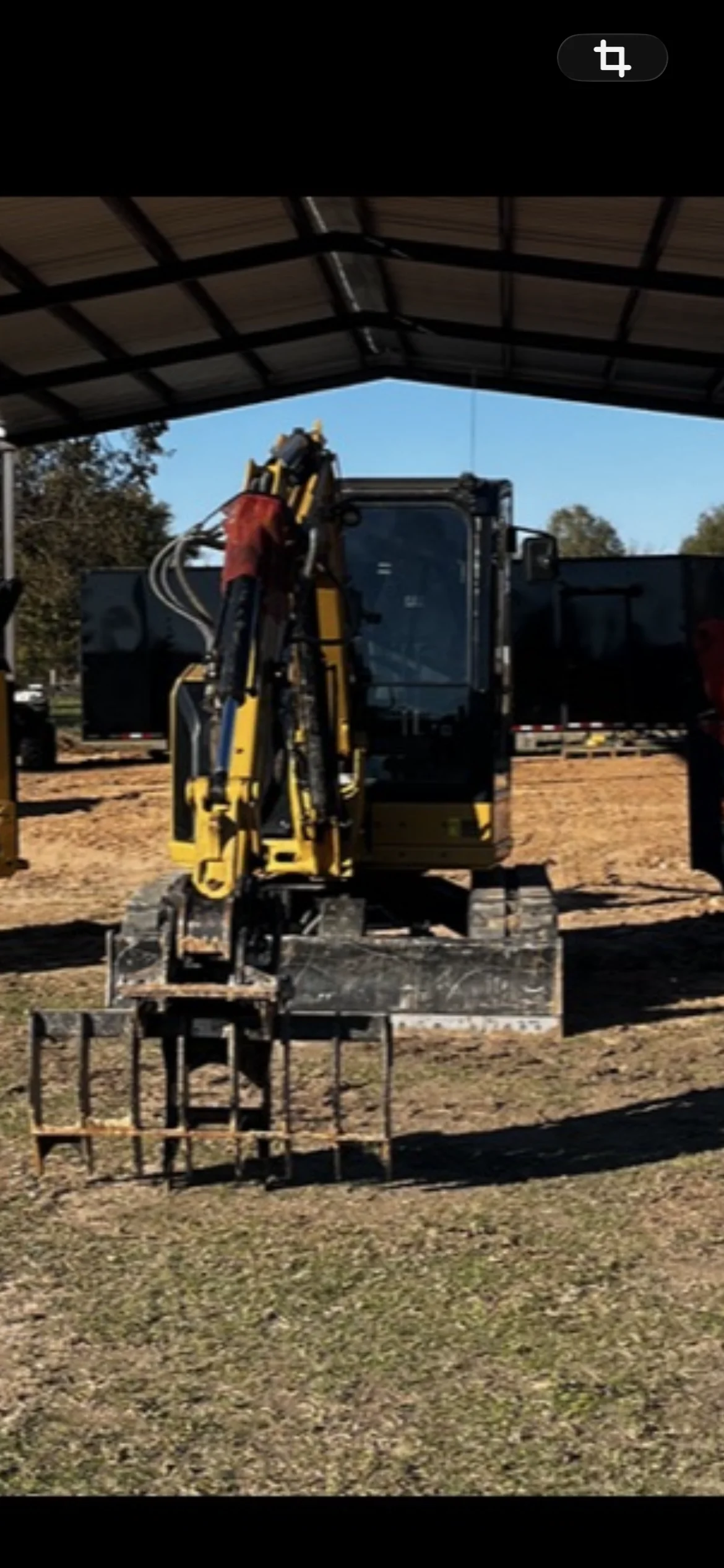 Yellow and black compact excavator mounted on flatbed truck with metal framework