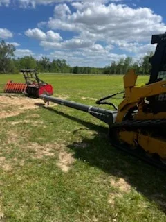 Tracked excavator with attachment clearing grass field, heavy equipment land preparation