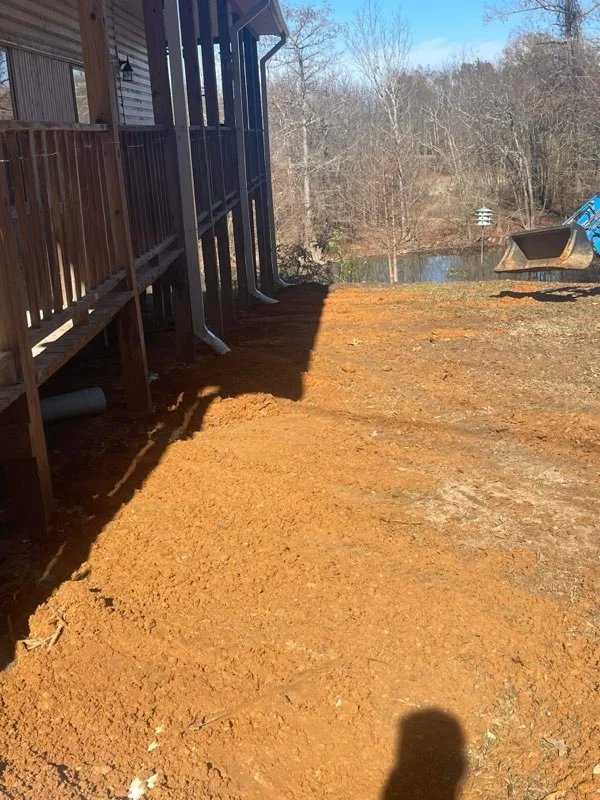Compacted clay driveway with graded surface and residential structures on wooded property