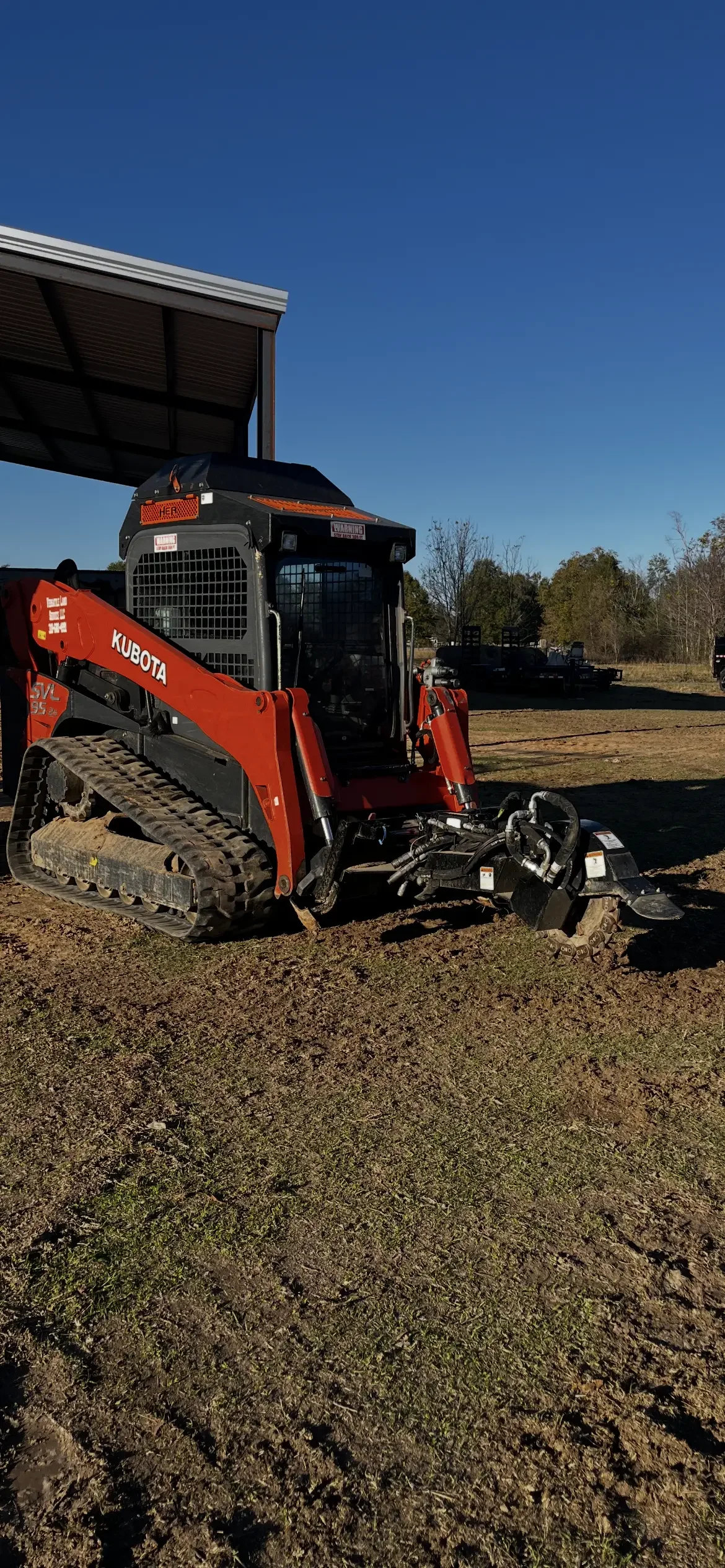 Red Kubota track loader with grading bucket on prepared dirt site