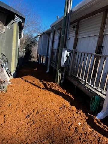 Cleared lot with red clay grading between mobile homes, debris removal complete