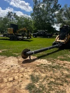Tracked excavator and heavy equipment on cleared land with exposed soil and green grass areas