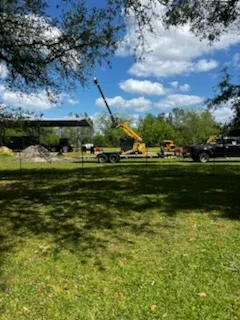 Cleared residential lot with heavy equipment, excavator and loader visible on manicured grass